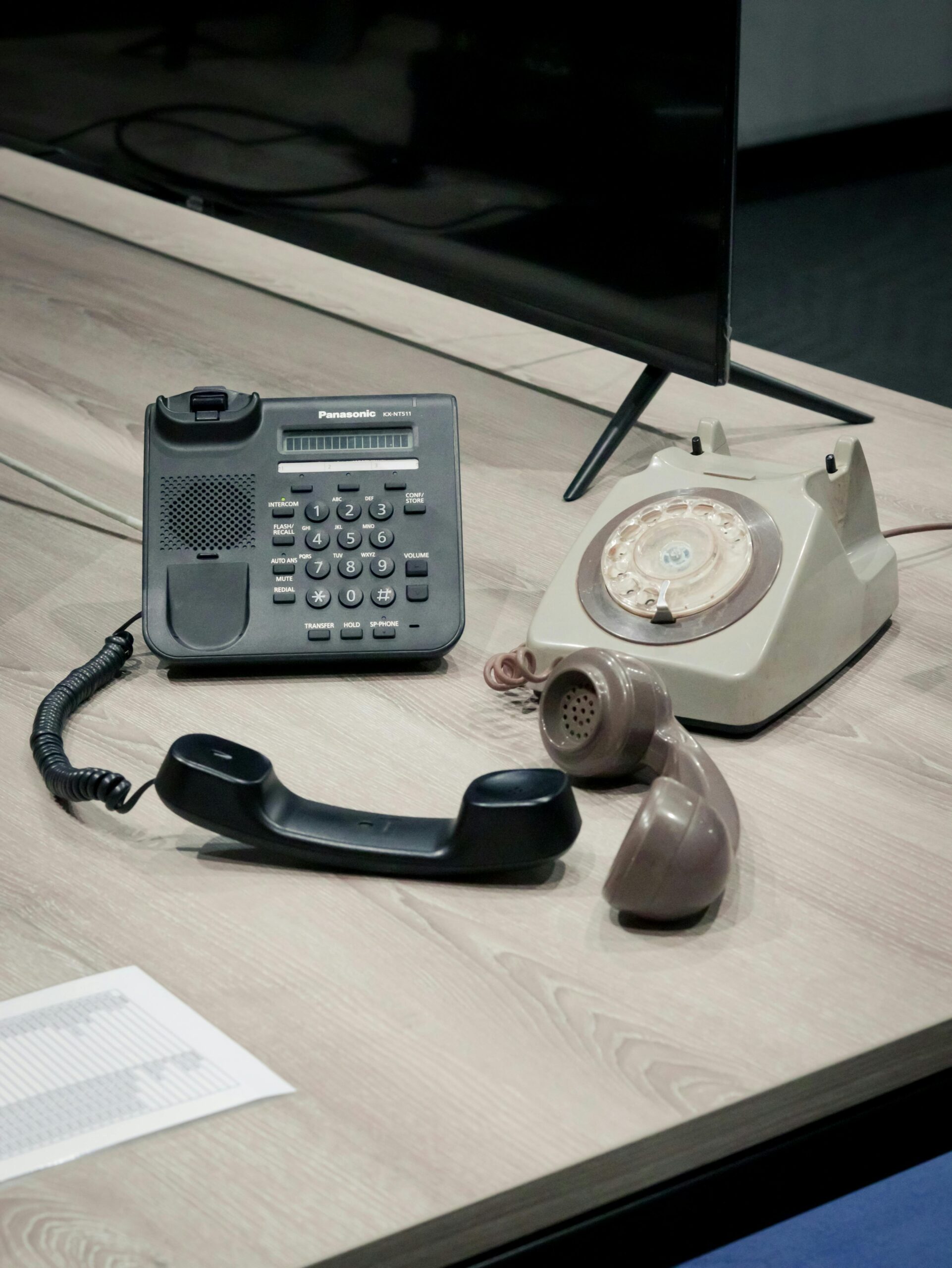 Contrasting vintage rotary and modern push-button phones on a desk in Malawi.